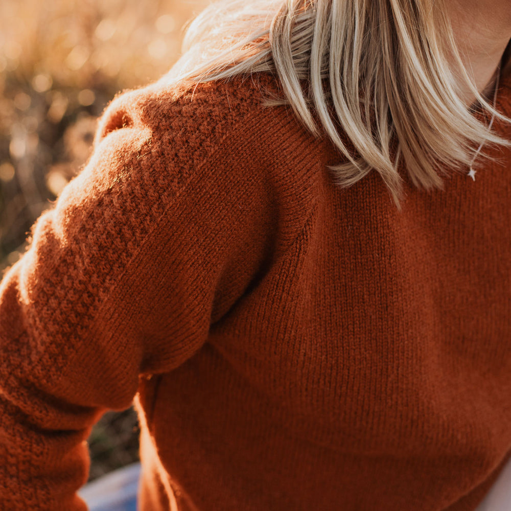 
                      
                        Close up shot of the arm detail of a McIvor Hill lambs' wool Mabel sweater in rust.
                      
                    